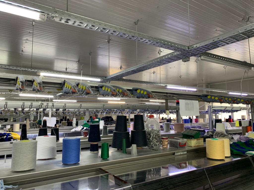 Yarn cones and STOLL flat knitting equipment inside Moga Knitworks factory